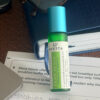 Avesta Head Space essential oil roll-on bottle in green glass with a turquoise cap, placed on a notebook and study papers on a desk.