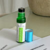 Avesta Head Space essential oil roll-on bottle in green glass bottle with a turquoise cap next to it, placed on a contract agreement on a table.