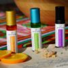 Avesta Morning Mate essential oil blend in an amber glass roller bottle with a gold cap, styled with fresh orange slices on a colourful textile background.